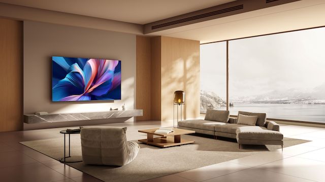 Una estancia moderna con Xiaomi TV A Pro 2026 montada en la pared, mostrando su vibrante pantalla. El interior está diseñado con muebles minimalistas, grandes ventanas que ofrecen una vista de la naturaleza y los tonos de color neutros, creando una atmósfera elegante y acogedora.