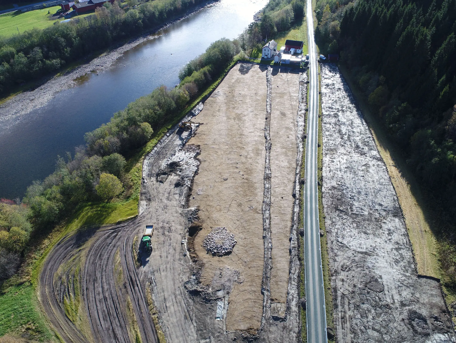 Disparo aéreo del sitio de excavación arqueológica cerca del río y la carretera en Noruega