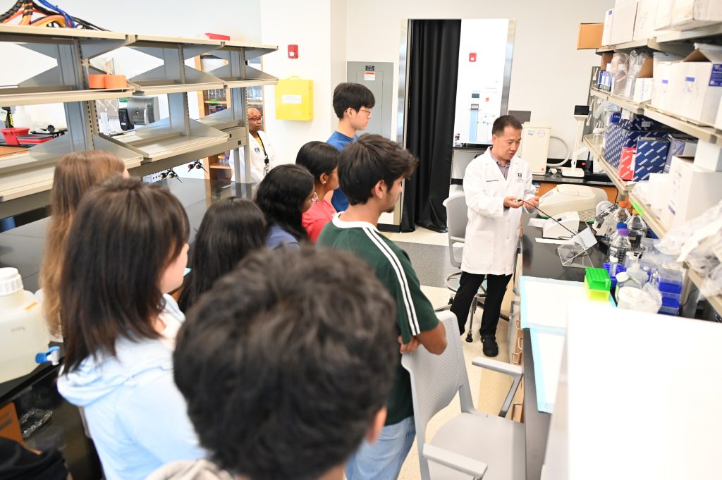 Un grupo de estudiantes de secundaria y universitarios visitan un laboratorio científico. Un científico les muestra diferentes equipos y cómo funciona.