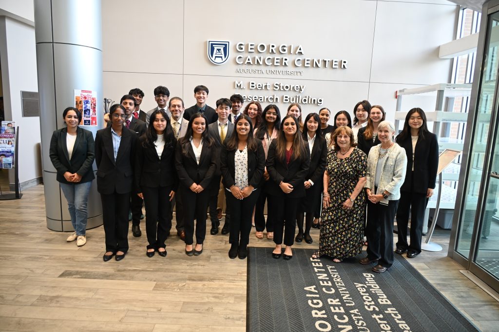 Un grupo de estudiantes de grupo y mujeres de la Shaol, junto con los miembros del Centro de Cáncer de Georgia, posando para una foto después de completar la experiencia de investigación de verano de 2025.
