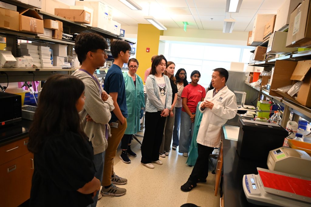 Un grupo de estudiantes de secundaria y universitarios visitan un laboratorio científico. Un científico les muestra diferentes equipos y cómo funciona.