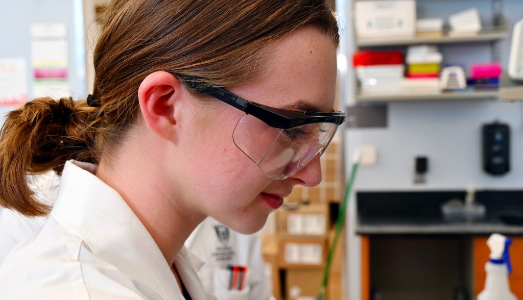 Un estudiante de secundaria que participa en un programa de académicos de verano aprende técnicas de laboratorio adecuadas.
