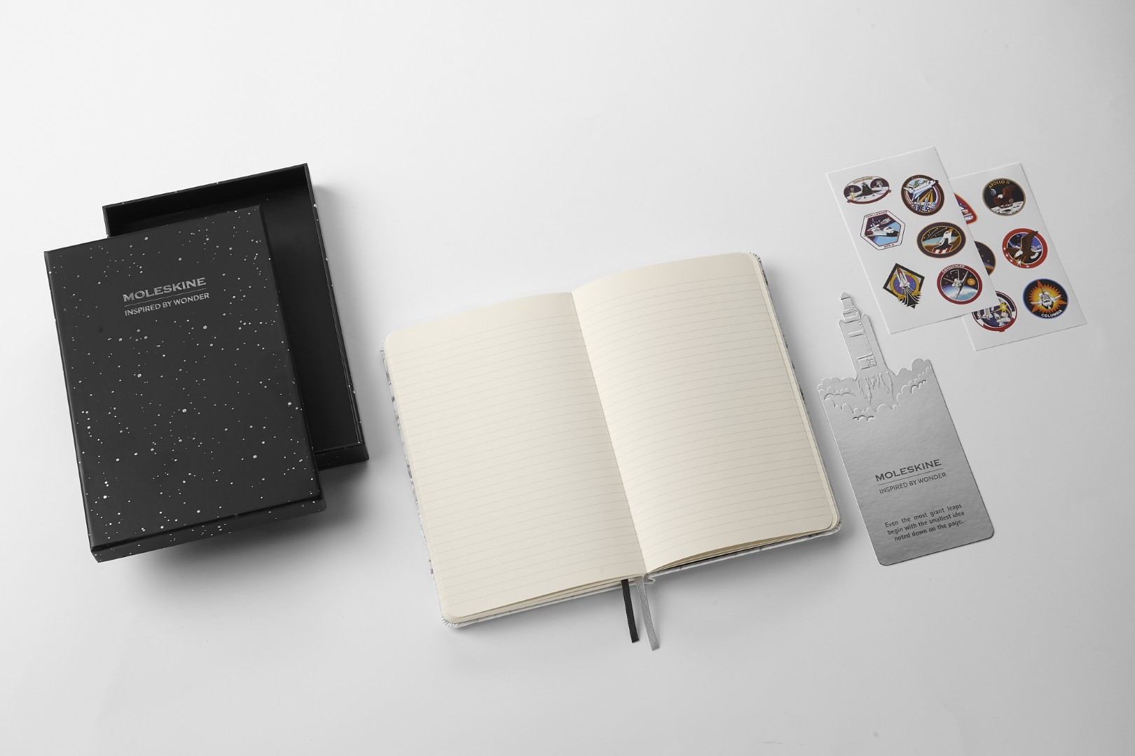 Notebook de edición limitada inspirada en la NASA por Moleskine Gift Bundle. Esto incluye: caja de regalo negra decorada con estrellas blancas, cuaderno de forro, marcador de cohetes que explota con una cita inspiradora (