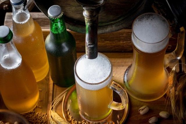 Las cervezas artesanales frías son vertidas por un grifo rústico rodeado de botellas y cereales, lo que refleja el proceso de manualidades detrás de la ciencia de la fermentación.