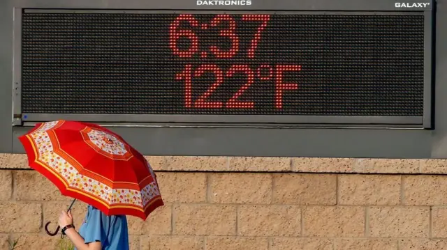 Una persona está cubierta por un paraguas cuando la temperatura alcanza los estándares de Celcius.