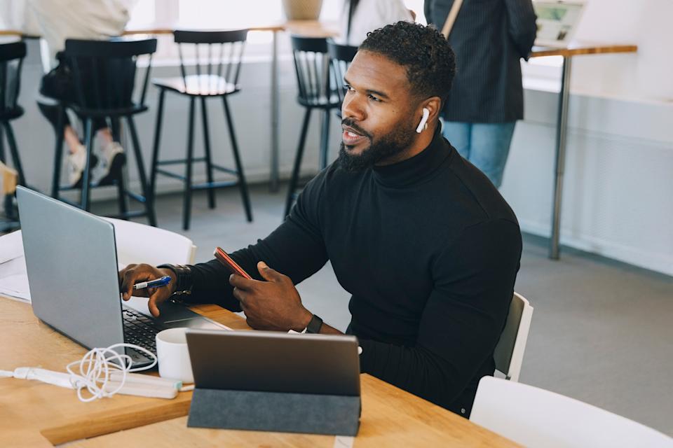 Un hombre frente a su computadora portátil usa AirPods