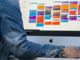 Persona que trabaja en una computadora con calendario en el monitor