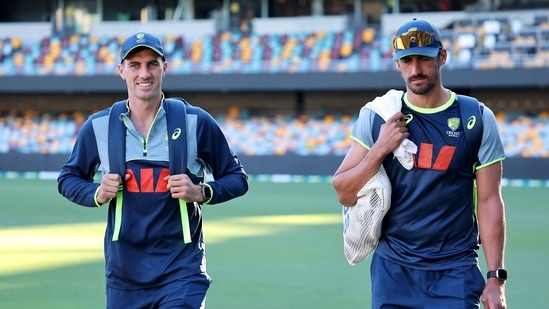 Pat Cummins y Mitchell Starc caminan juntos antes de un entrenamiento en el Gabba. (AFP)