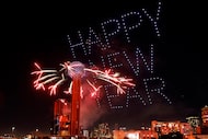 Los fuegos artificiales explotan desde la Torre Reunión mientras los drones crean iluminación 