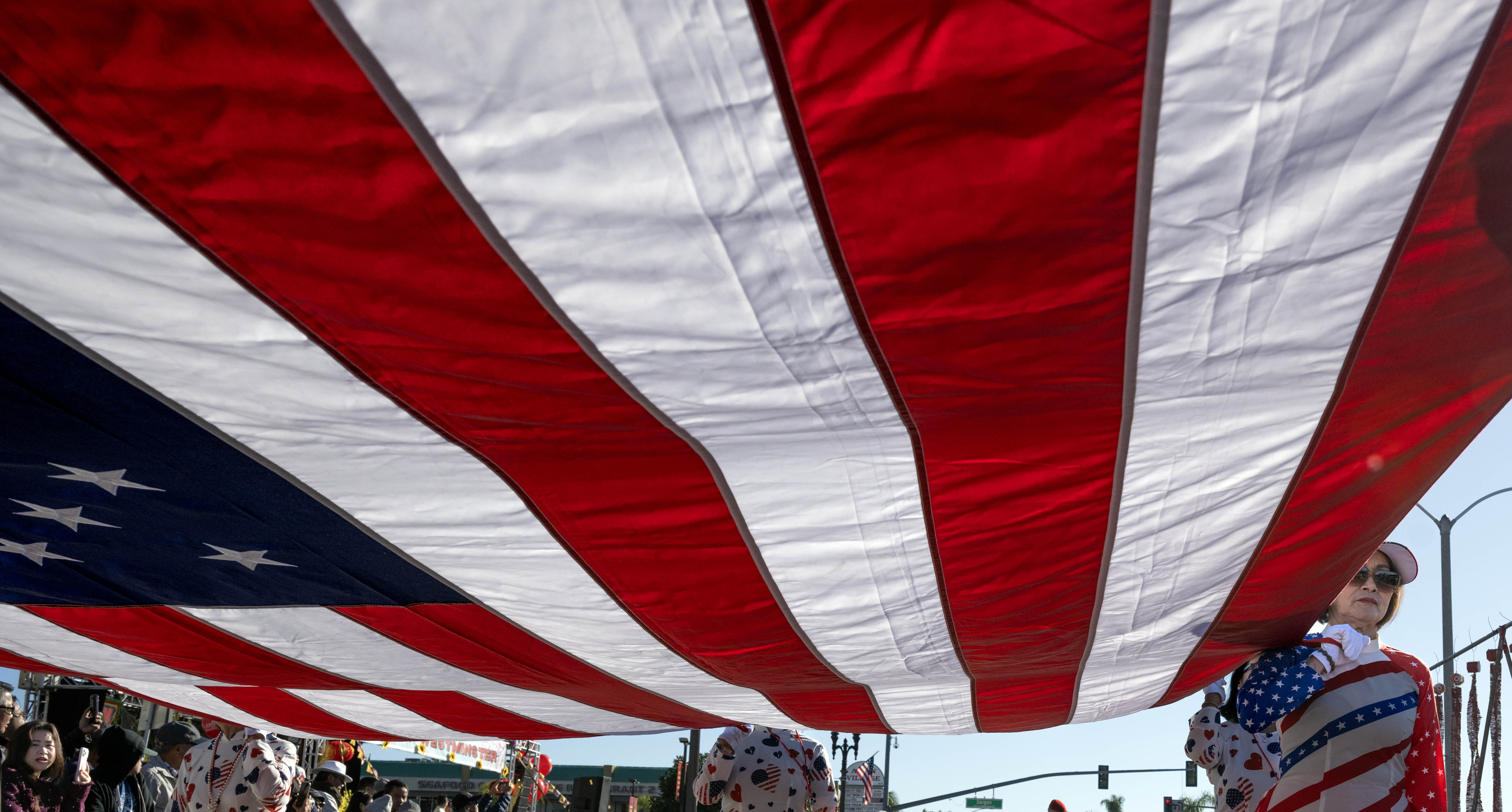 El grupo de voluntarios de Little Saigon lleva una gran bandera estadounidense...